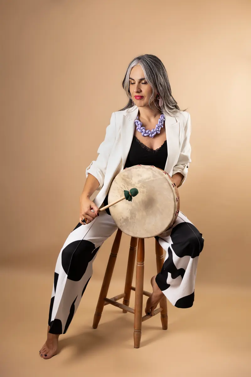 Pili Valencia sentada en un taburete, con un tambor de mano sobre las piernas.